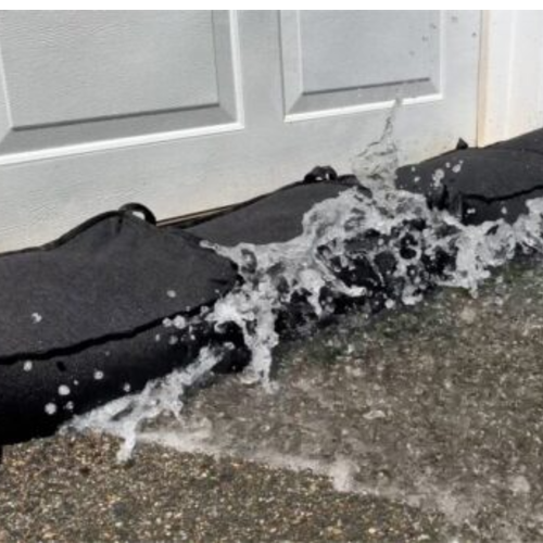 Close-up of Minnow gel-filled water-absorbing flood bags blocking incoming floodwater near a door